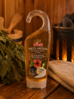 Pirts medus ar karstā medus aromātu 290 g caurspīdīgā pudelē ar dozatoru novietots uz koka lāvas pirts interjerā. Blakus redzama pirts slota un dvielis.
