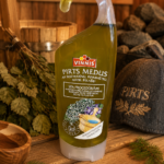 Pirts medus ar rozmarīnu, piparmētru, nātri un eikaliptu plastmasas pudelē novietots uz koka lāvas pirts interjerā. Fonā redzama pirts slota, koka ķipis, koka bļoda un pirts cepure.