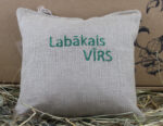 Aromātiskais spilventiņš ar uzrakstu "Labākais VĪRS" novietots uz siena fona.
