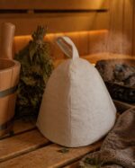 Balta pirts cepure uz koka sola tradicionālā pirtī blakus slotiņām un koka ķipītim