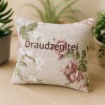 ALT Aromātiskais auduma spilventiņš ar uzrakstu “Draudzenītei”, novietots uz gaišas koka virsmas