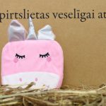 Rozā bērnu vannas švammīte vienradža formā novietota uz salmiem dekoratīva fona priekšplānā. Attēlā izcelts vienradža dizains ar sudrabainu ragu, ausīm un izšūtām sejas detaļām.