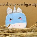 Zila bērnu vannas švammīte vienradža formā novietota uz salmiem dekoratīva fona priekšplānā. Attēlā izcelta švammītes priekšpuse ar sudrabainu ragu, ausīm un izšūtām sejas detaļām.