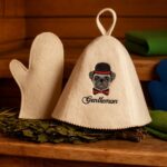 Pirts cepure “Gentleman” ar izšūtu suņa motīvu un cilpu pakarināšanai, novietota uz pirts lāvas blakus pirts dūrainim