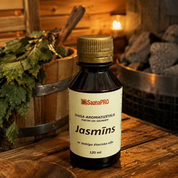 Gaisa aromatizētājs pirtīm ar jasmīna aromātu 120 ml tumšā stikla pudelē novietots uz koka galda pirts interjerā. Blakus redzams koka pirts spainis ar slotu, pirts krāsns akmeņi un aizdegta svece.