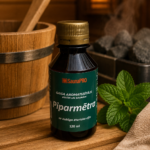 Gaisa aromatizētājs Piparmētra 120 ml tumšā pudelē novietots uz koka lāvas pirts interjerā. Blakus redzama svaiga piparmētra, dvielis un fonā – koka spainis un pirts krāsns.