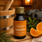 Gaisa aromatizētājs Apelsīns 120 ml tumšā pudelē novietots uz koka lāvas pirts interjerā. Blakus redzami svaigi apelsīni, egles zars, dvielis un fonā – koka spainis un pirts krāsns.