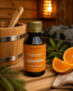 Gaisa aromatizētājs Apelsīns 120 ml tumšā pudelē novietots uz koka lāvas pirts interjerā. Blakus redzami svaigi apelsīni, egles zars, dvielis un fonā – koka spainis un pirts krāsns.