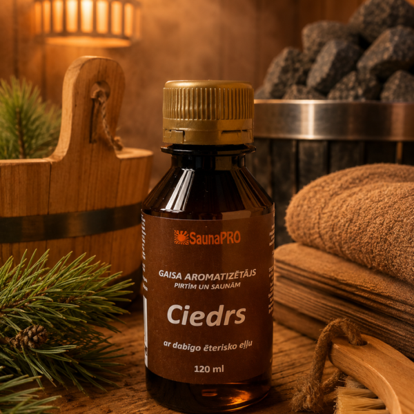 Gaisa aromatizētājs pirtīm ar ciedra aromātu 120 ml tumšā stikla pudelē novietots uz koka galda pirts interjerā. Blakus redzams koka pirts spainis, pirts krāsns akmeņi, salocīti dvieļi un skuju zari.