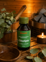 Gaisa aromatizētājs pirtīm ar eikalipta aromātu 120 ml tumšā stikla pudelē novietots uz koka galda pirts interjerā. Blakus redzams koka pirts spainis ar kausiņu, eikalipta zari un aizdegta svece.