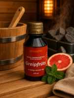 Gaisa aromatizētājs Greipfrūts 120 ml tumšā pudelē novietots uz koka lāvas pirts interjerā. Blakus redzams svaigs greipfrūts, piparmētra, dvielis un fonā – koka spainis un pirts krāsns.