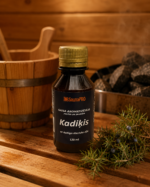 Gaisa aromatizētājs pirtīm ar kadiķa aromātu 120 ml tumšā stikla pudelē novietots uz koka galda pirts interjerā. Blakus redzams koka pirts spainis, pirts krāsns akmeņi un kadiķa zari.