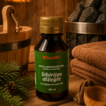 Gaisa aromatizētājs pirtīm ar Sibīrijas dižegles aromātu 120 ml tumšā stikla pudelē novietots uz koka galda pirts interjerā. Blakus redzams koka pirts spainis, pirts krāsns akmeņi, salocīti dvieļi un egļu zari.