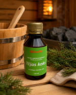 Gaisa aromatizētājs pirtīm ar tējas koka aromātu 120 ml tumšā stikla pudelē novietots uz koka galda pirts interjerā. Blakus redzams koka pirts spainis ar kausiņu, egļu zari un pirts dvielis.