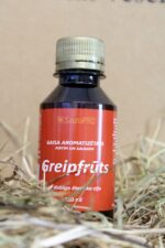 Gaisa aromatizētājs pirtīm un saunām "Greipfrūts" uz salmu fona. Attēlā redzama tumša plastmasas pudele ar sarkanu etiķeti un skrūvējamu vāciņu.