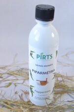 Pirts aromāts “Piparmētra” baltā pudelē ar melnu vāciņu, novietots uz salmu klājuma gaišā vidē