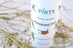 Pirts aromāts “Piparmētra” baltā pudelē ar piparmētru dizainu, novietots uz salmu klājuma