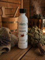 Pirts aromatizators ar lavandas aromātu 500 ml baltā pudelē novietots uz koka lāvas pirts interjerā. Priekšplānā redzami lavandas ziedi un dvielis, fonā pirts krāsns ar akmeņiem un ozola pirtsslota.