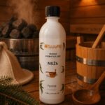 Pirts aromatizators ar meža aromātu 500 ml baltā pudelē novietots uz koka lāvas pirts interjerā. Fonā redzama pirts krāsns ar akmeņiem, koka spainis un pirts cepure.