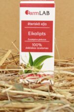 FarmLAB eikalipta ēteriskā eļļa iepakojumā novietota uz salmiem, redzams produkta iepakojums ar eikalipta lapu attēlu