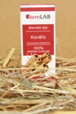 FarmLAB kanēļa ēteriskā eļļa iepakojumā novietota uz salmiem, redzams produkta iepakojums ar kanēļa standziņu attēlu