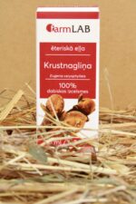 FarmLAB krustnagliņu ēteriskā eļļa iepakojumā novietota uz salmiem, redzams produkta iepakojums ar krustnagliņu attēlu