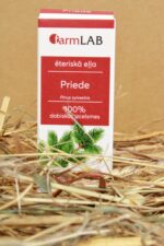 FarmLAB priedes ēteriskā eļļa iepakojumā novietota uz salmiem, redzams produkta iepakojums ar priedes zaru attēlu