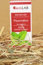 FarmLAB piparmētru ēteriskā eļļa iepakojumā novietota uz salmu paklāja, redzams produkta iepakojums ar piparmētru lapu attēlu