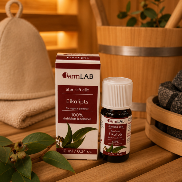 FarmLab ēteriskā eļļa "Eikalipts" 10 ml kopā ar iepakojumu novietota uz koka lāvas pirts interjerā. Blakus redzama pirts cepure, eikalipta zari, koka ķipis un pirts akmeņi.