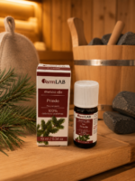FarmLab ēteriskā eļļa "Priede" 10 ml kopā ar iepakojumu novietota uz koka lāvas pirts interjerā. Blakus redzami priedes zari, pirts cepure, koka ķipis un pirts akmeņi.