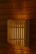Koka pirts sienas lampa ar vertikālu aizsargrežģi, uzstādīta pie koka sienas pirts telpā