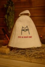 Balta filca pirts cepure ar uzrakstu “I’m a cool cat”, skats no priekšpuses, novietota uz salmiem uz kartona pamatnes