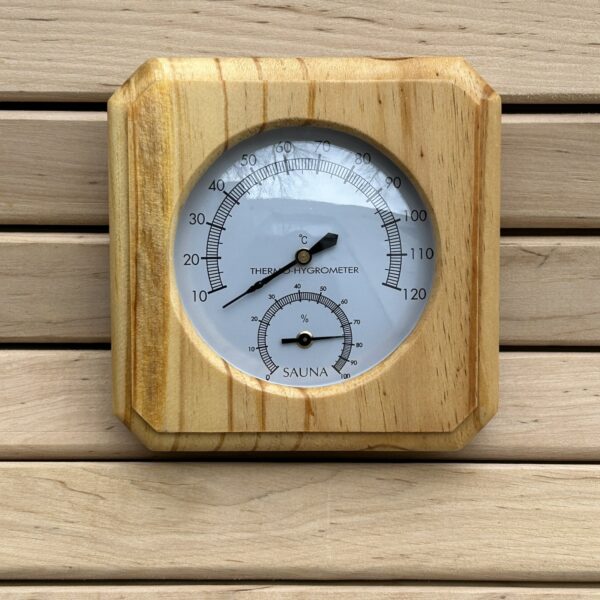 Pirts termometrs ar higrometru tuvplānā uz koka sienas