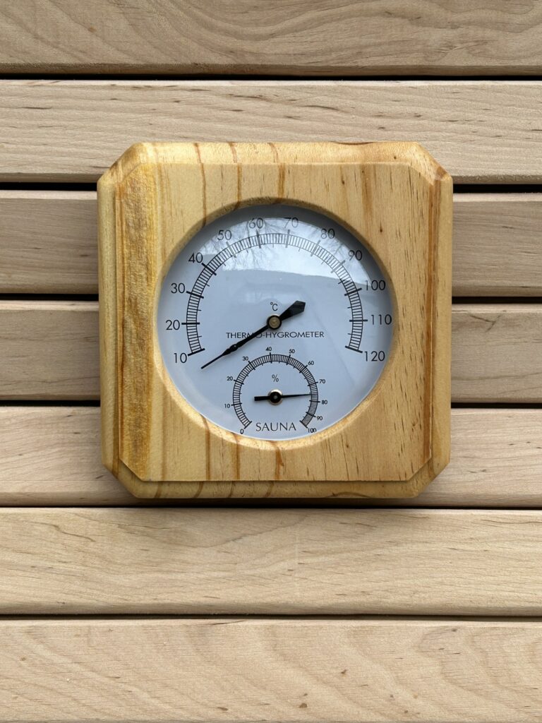 Pirts termometrs ar higrometru tuvplānā uz koka sienas