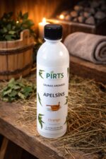Saunas aromāts “Apelsīns” baltā pudelē uz koka galda pirts interjerā ar slotiņām un sveces gaismu