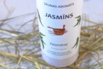 Saunas aromāts “Jasmīns” baltā pudelē tuvplānā uz gaiša salmu klājuma