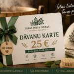 Dāvanu karte 25 € novietota pirts atmosfērā uz koka lāvas. Attēlā redzama "Īstas Pirts Lietas" dāvanu karte ar zaļu lenti, pirts cepure un pirts piederumi, radot siltu un svinīgu noskaņu.