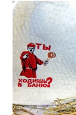 Tuvplāns baltai filca pirts cepurei ar sarkanu izšuvumu "Ты ходишь в баню?" uz gaiša fona. Attēlā redzama izšuvuma detaļa un cepures filca faktūra.